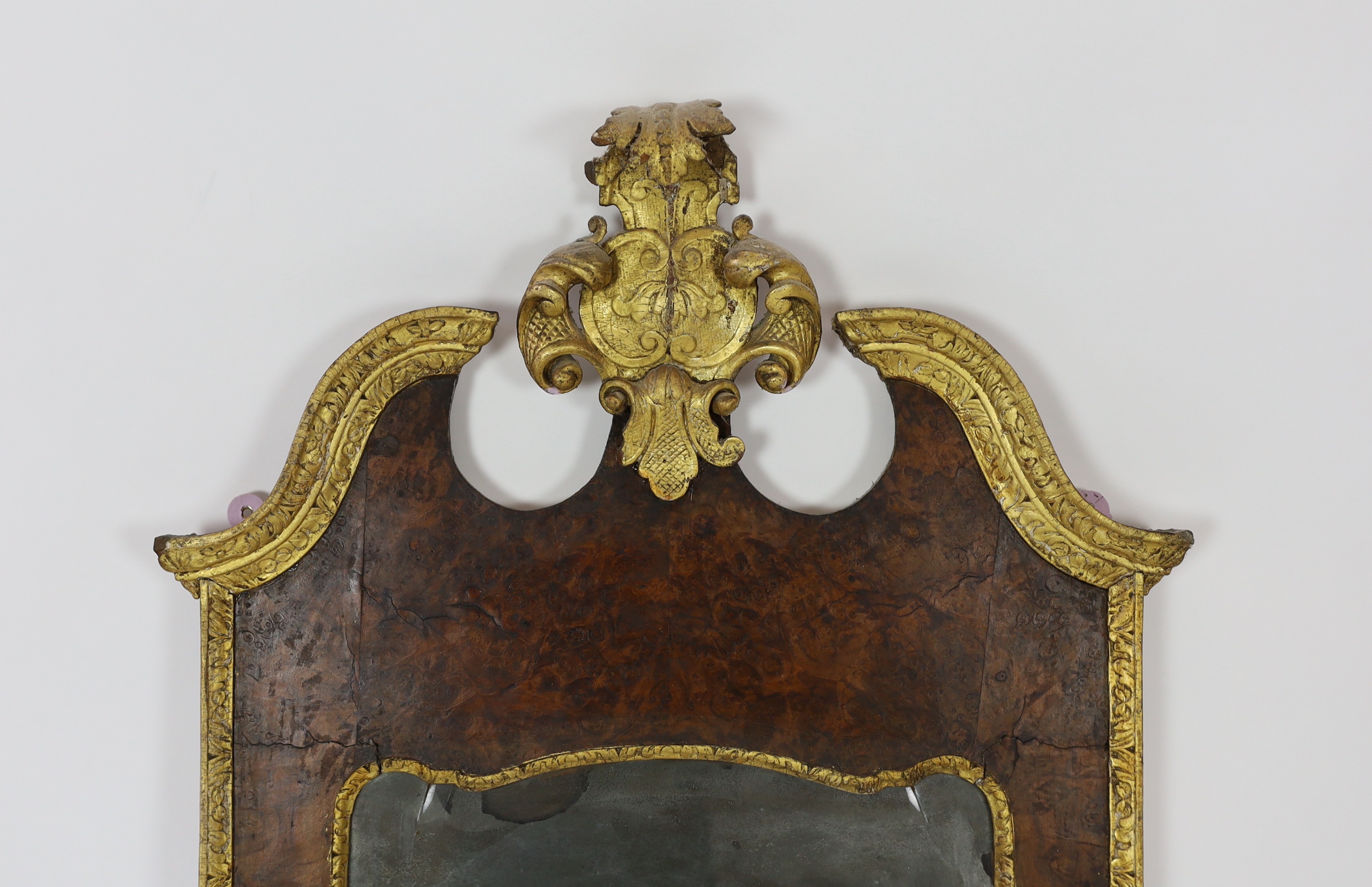 A George II and later carved giltwood and burr walnut wall mirror, 133.5cm high, 69cm wide